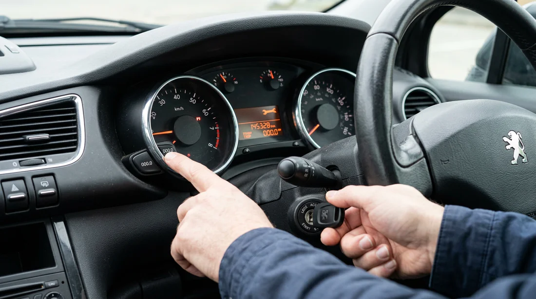 Main appuyant sur le bouton 000 de remise à zéro de la Peugeot 3008